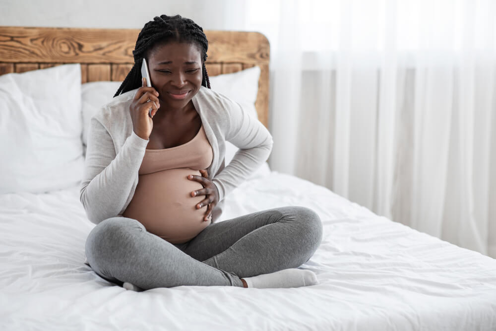 Pregnant Lady Feeling Pain in Belly, Calling Doctor on Cellphone While Sitting on Bed at Home, Suffering From Abdominal Ache