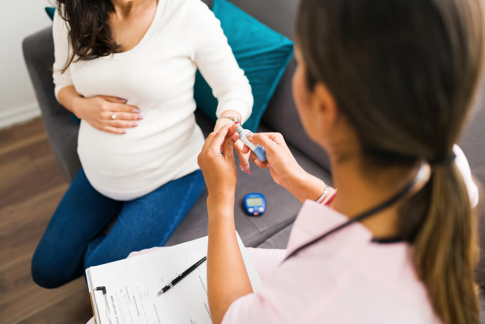 Professional Nurse Measuring With a Medical Device in the Finger the Blood Sugar Levels of a Caucasian Pregnant Woman