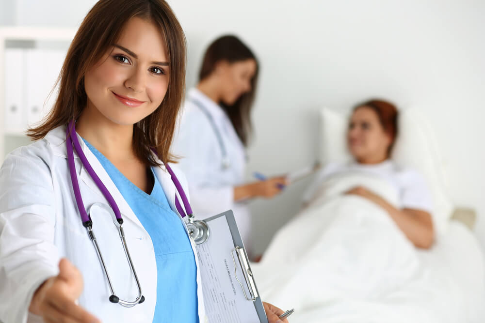 Female Doctor Offering Hand to Shake While Patient Lying in Bed 