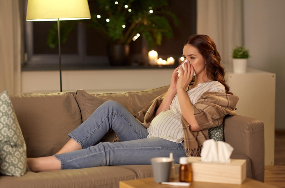 Pregnancy and People Concept - Sick Pregnant Woman Blowing Nose With Paper Tissue at Home