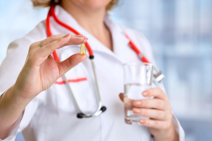 Doctor Holding a Fish Oil Capsule and a Glass of Water