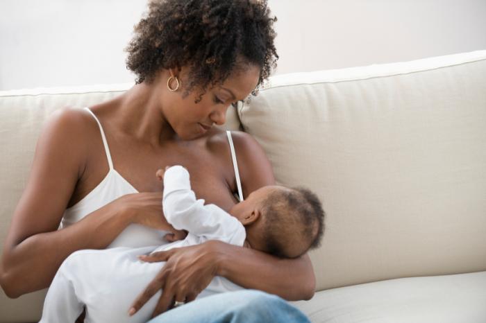 African American Mother Breastfeeding Her Baby on a Sofa
