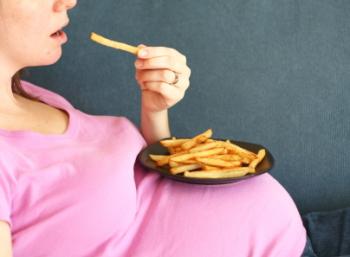 Pregnant Woman Eating French Fries From a Plate on her Stomach