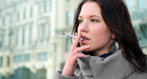 Brown Haired Woman in a Grey Coat Smoking