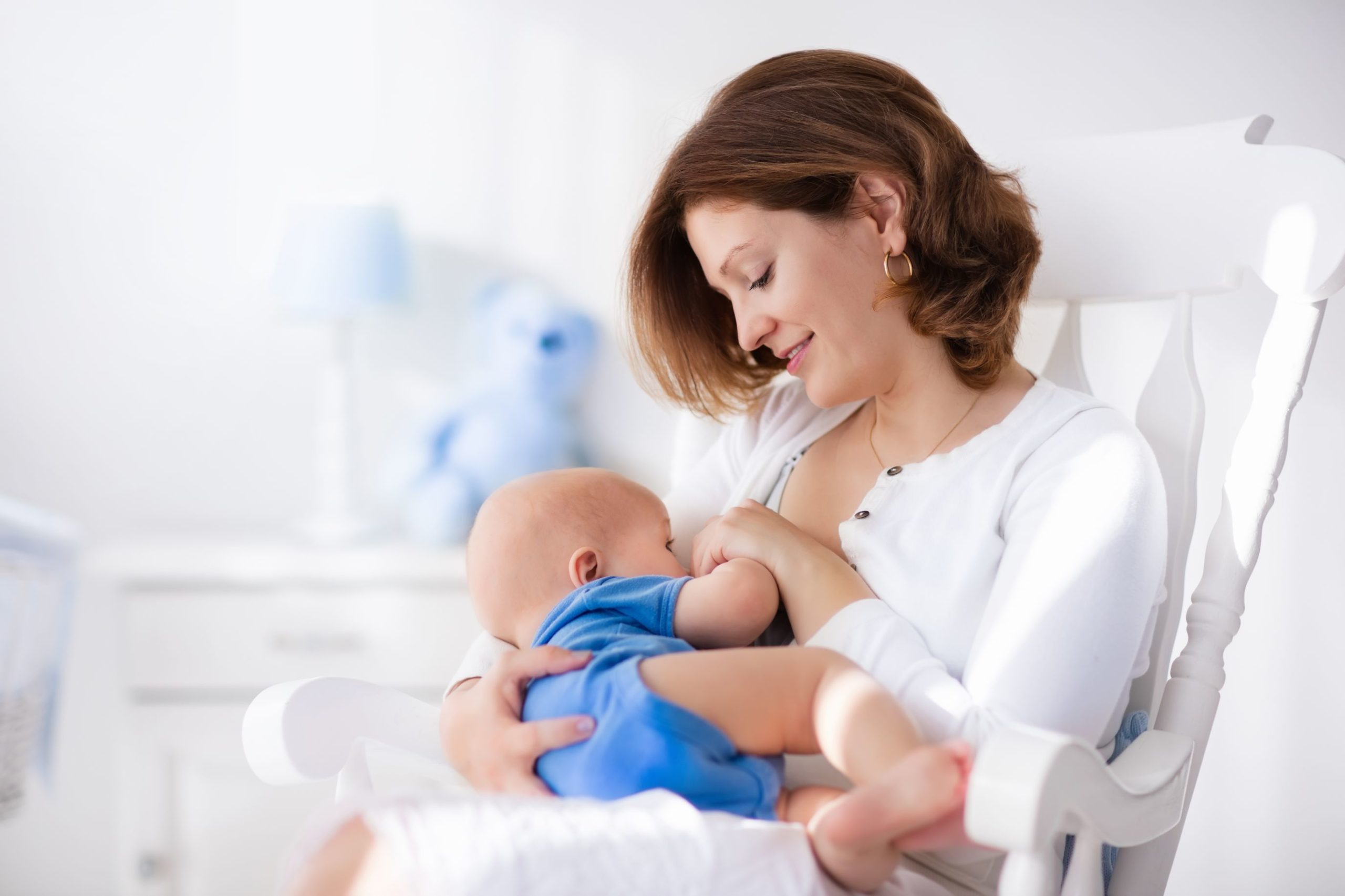 Woman Sitting in a Rocking Chair and Breastfeeding Her Baby