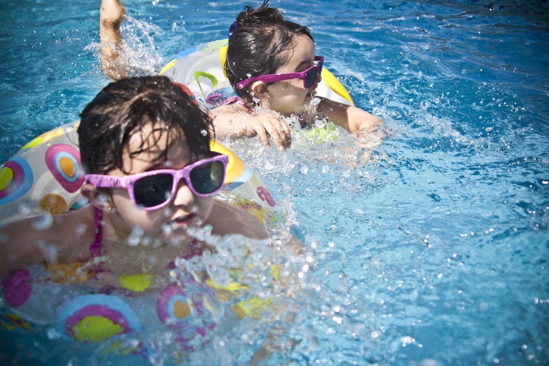Two Young Girls With Pink Sunglasses Swimming in the Pool