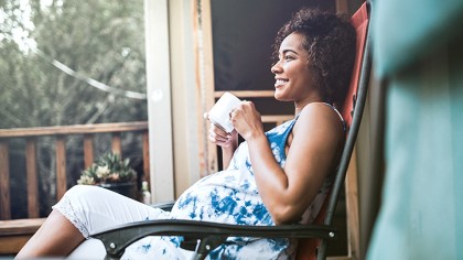 Pregnant woman Sitting on the Porch with a Cup in her Hands