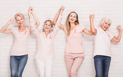 Several Woman Holding Their Hands Up in the Air Smiling