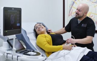 Bald Doctor in Black Shirt Doing an Ultra Sound Examination on a Pregnant Woman