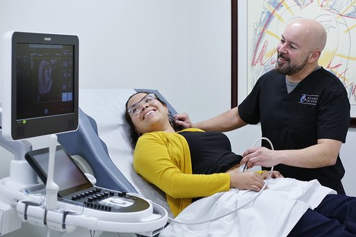 Bald Doctor in Black Shirt Doing an Ultra Sound Examination on a Pregnant Woman