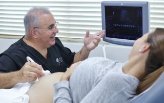 Doctor Showing an Ultrasound Image on the Screen to a Pregnant Patient