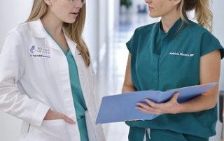 Two Blonde Female Doctors Standing and Talking in the Hallway