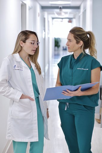 Two Blonde Female Doctors Standing and Talking in the Hallway