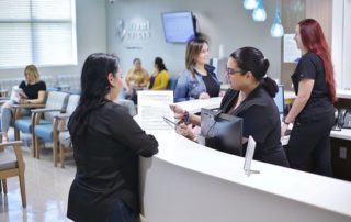 Woman Filling Out Forms at the Reception Desk at a Clinic