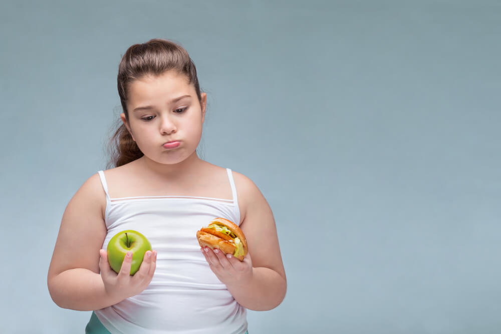 Girl Child Overweight Holding a Green Apple and a Hamburger