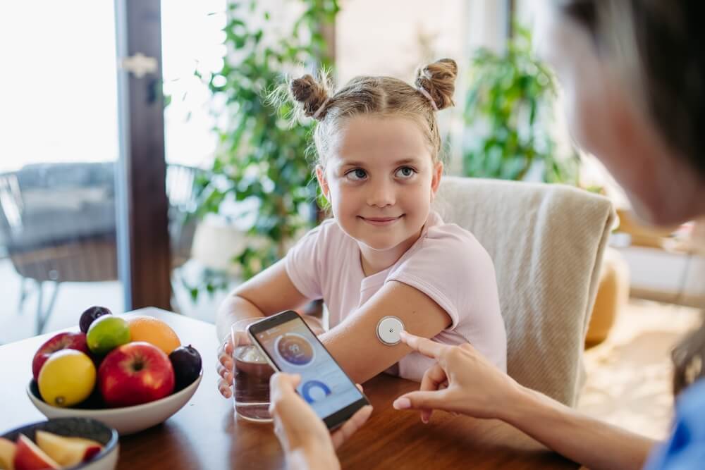 Girl With Diabetes Checking Blood Glucose Level at Home Using Continuous Glucose Monitor.