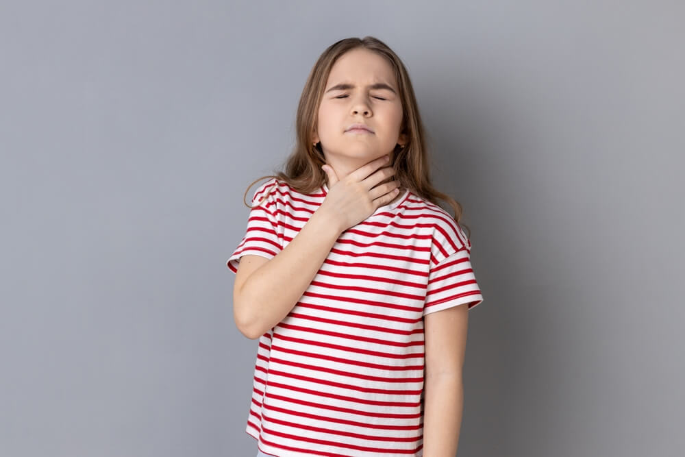 Portrait of Little Girl Wearing Striped T-Shirt Touching Neck, Suffering Thyroid Disorder