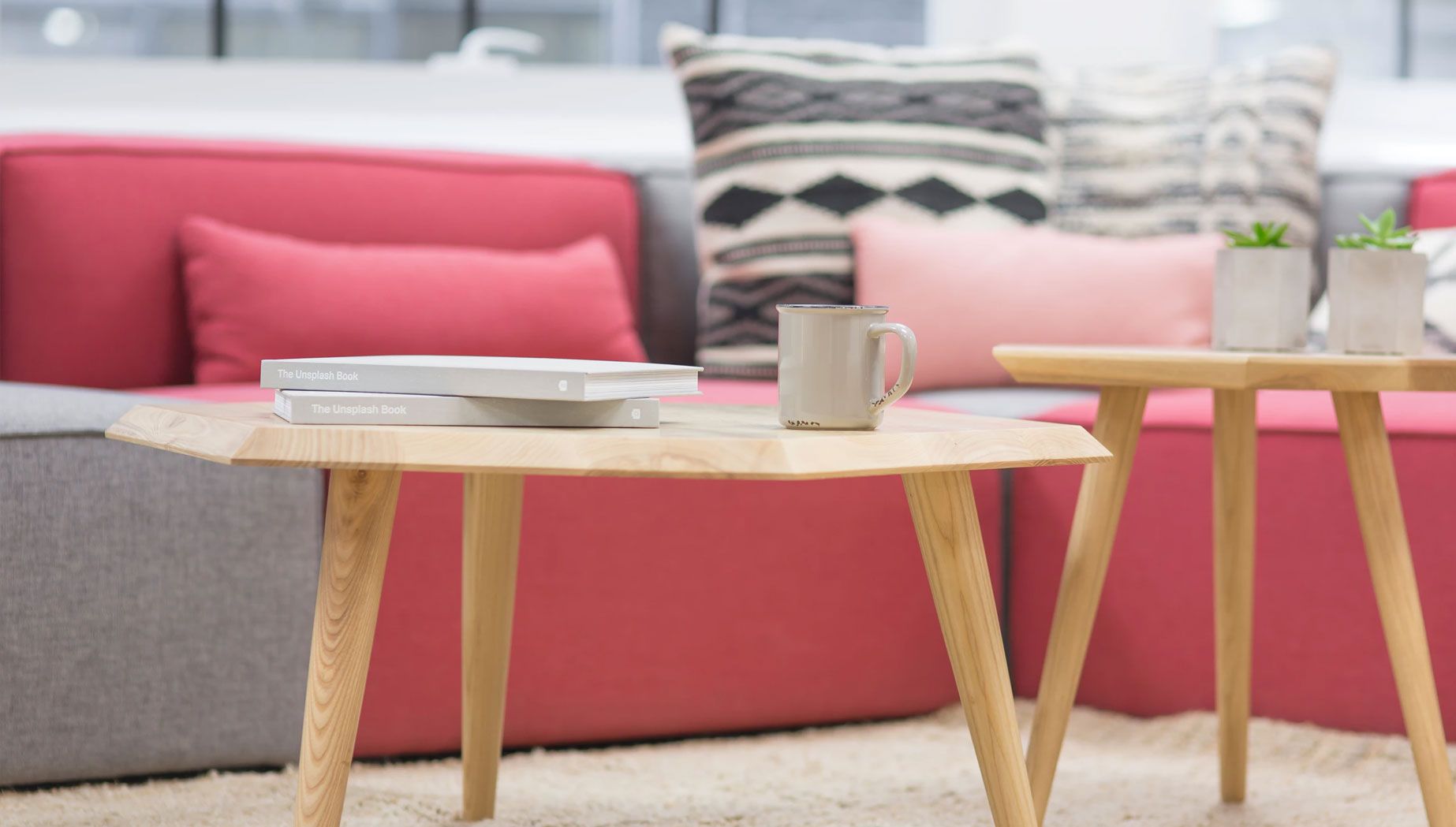 Two Wooden Desks in Front of a Pink and Grey Sofa