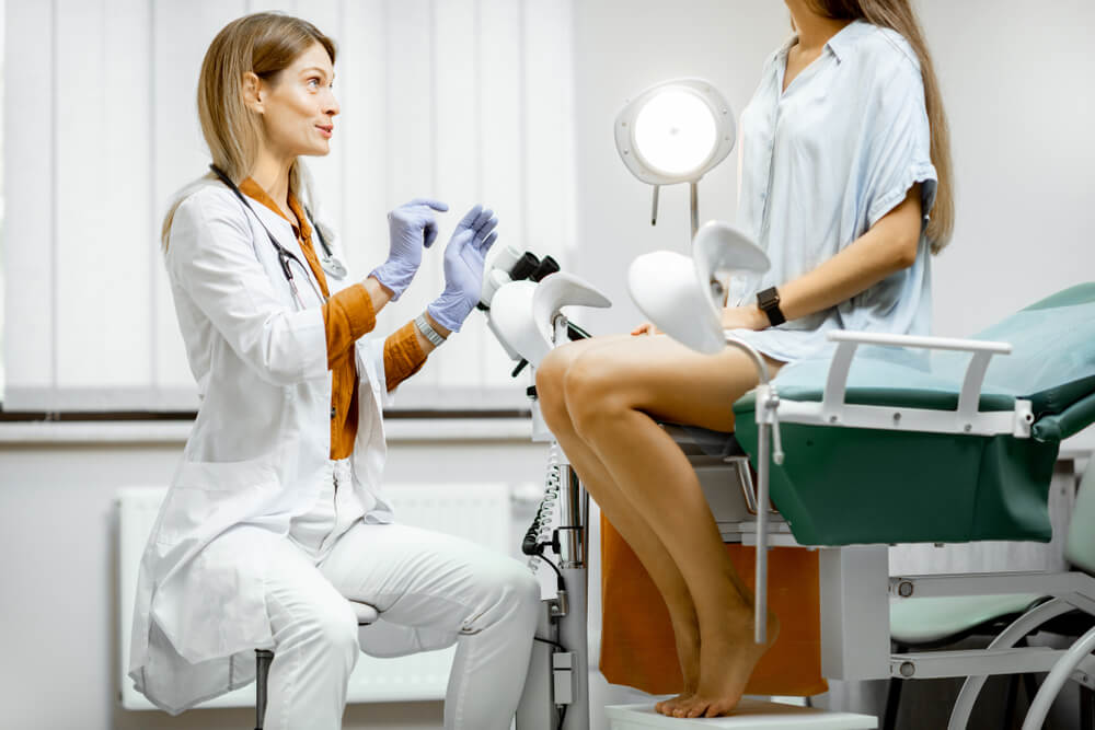 Gynecologist Preparing for an Examination Procedure for a Pregnant Woman Sitting on a Gynecological Chair in the Office