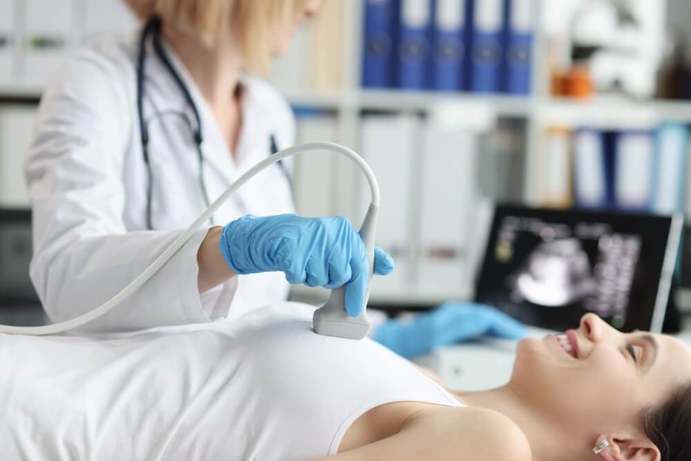 Doctor Doing Ultrasound Examination of Breast of Patient in Clinic