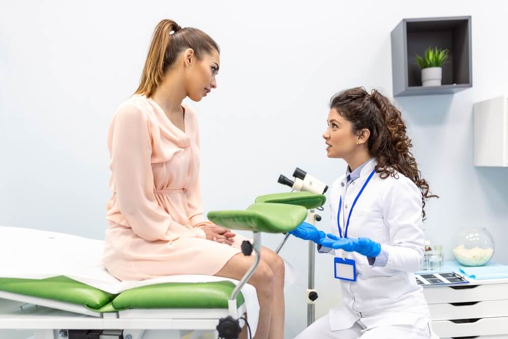 Gynecologist Preparing for an Examination Procedure for a Pregnant Woman Sitting on a Gynecological Chair in the Office