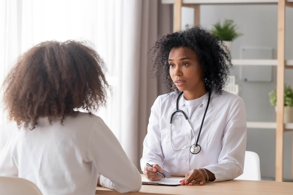 Male Doctor With Female Patient Reading Reports on Paper