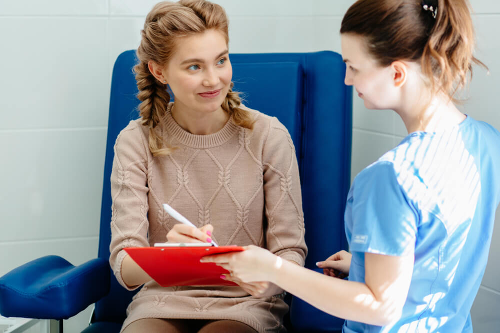 A Young Woman Sitting, Consulting the Doctor About Signing Paper