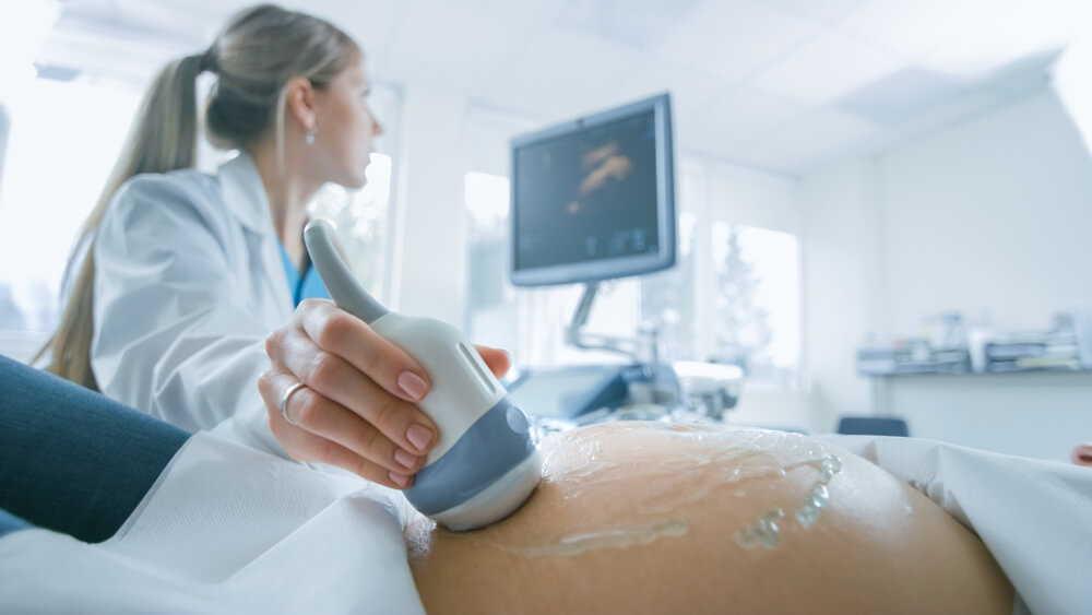 In the Hospital, Close-up Shot of the Doctor Does Ultrasound Sonogram Procedure to a Pregnant Woman.