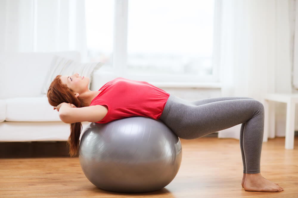 Fitness, Home and Diet Concept - Smiling Redhead Girl Exercising With Fitness Ball at Home