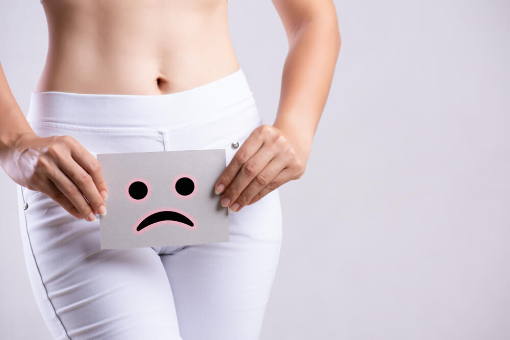 Closeup Young Woman Holding Paper With Sad Smiley Face or Unhappy Near Her Crotch Lower Abdomen.