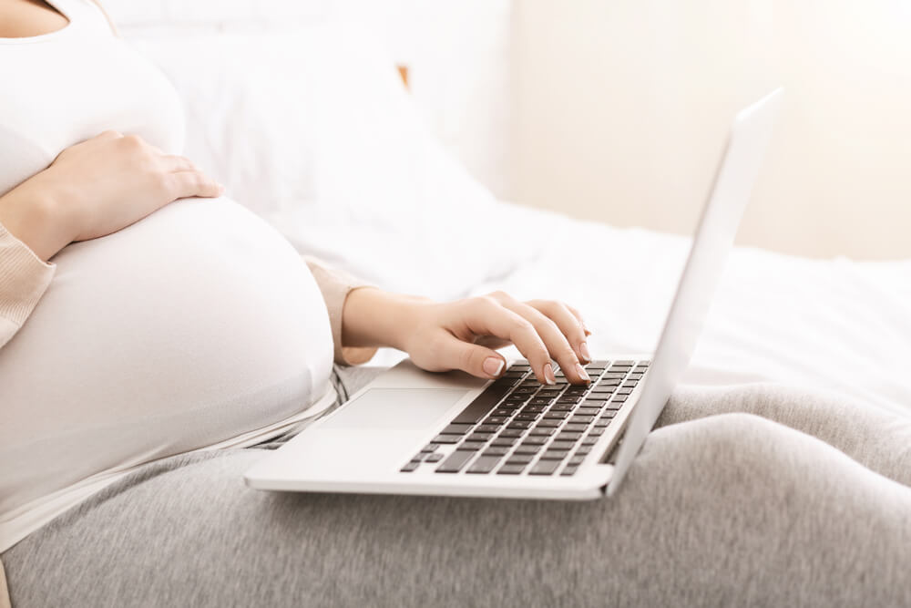 Pregnant Woman Browsing on Laptop at Home, Side View, Free Space