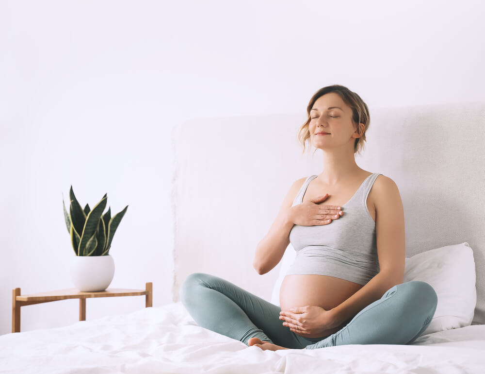 Pregnant Woman in Lotus Pose Doing Meditation or Breathing Exercises for Healthy Pregnancy and Preparing Body for Childbirth