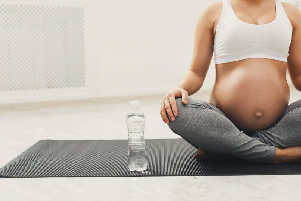 A Pregnant Woman Drinking Water During Yoga Training