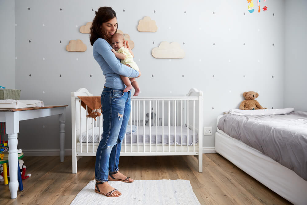 Mother Comforting Newborn Baby Son In Nursery