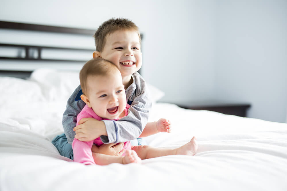 Toddler Baby Boy Kisses His Happy Brother on Bed