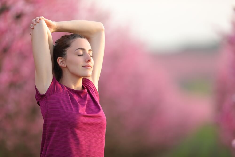 A woman stretching arms and relaxing in a field after sport