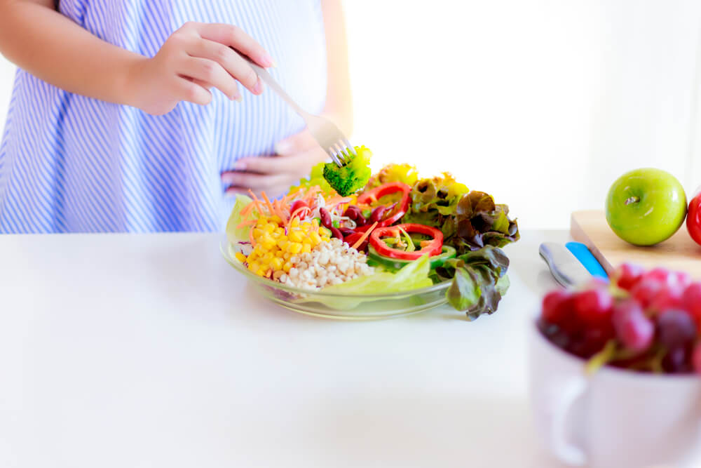 Health Concept A Pregnant Girl Is Using A Fork To Get Broccoli For Eating In The Salad Dish