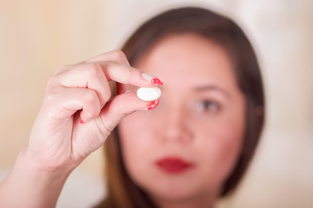 Portrait of a young woman holding in her hand a soft gelatin vaginal tablet or suppository