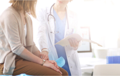 clinical-research-service-box | New Age Women's Health Doctor Reading Patient's Form In Front of Her
