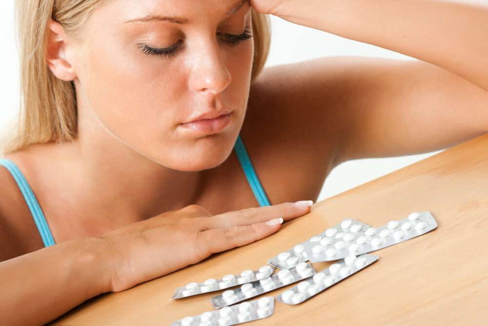 Girl Looking at Pills on the Table, Taking Pills
