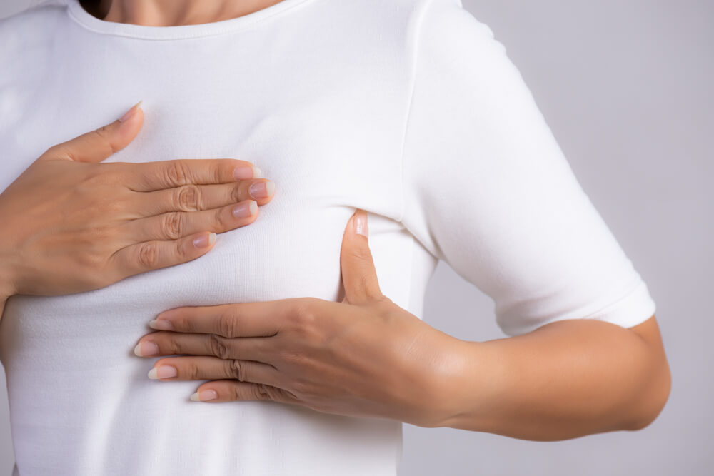 Woman Hand Checking Lumps on Her Breast for Signs of Breast Cancer On