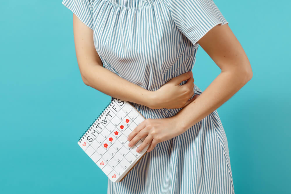 Woman in Blue Dress Holding Periods Calendar for Checking Menstruation Days
