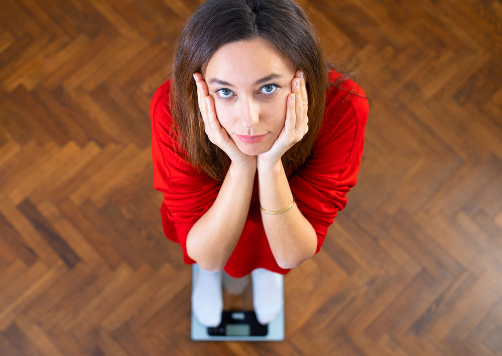 Sad Young Woman Standing on Scale.