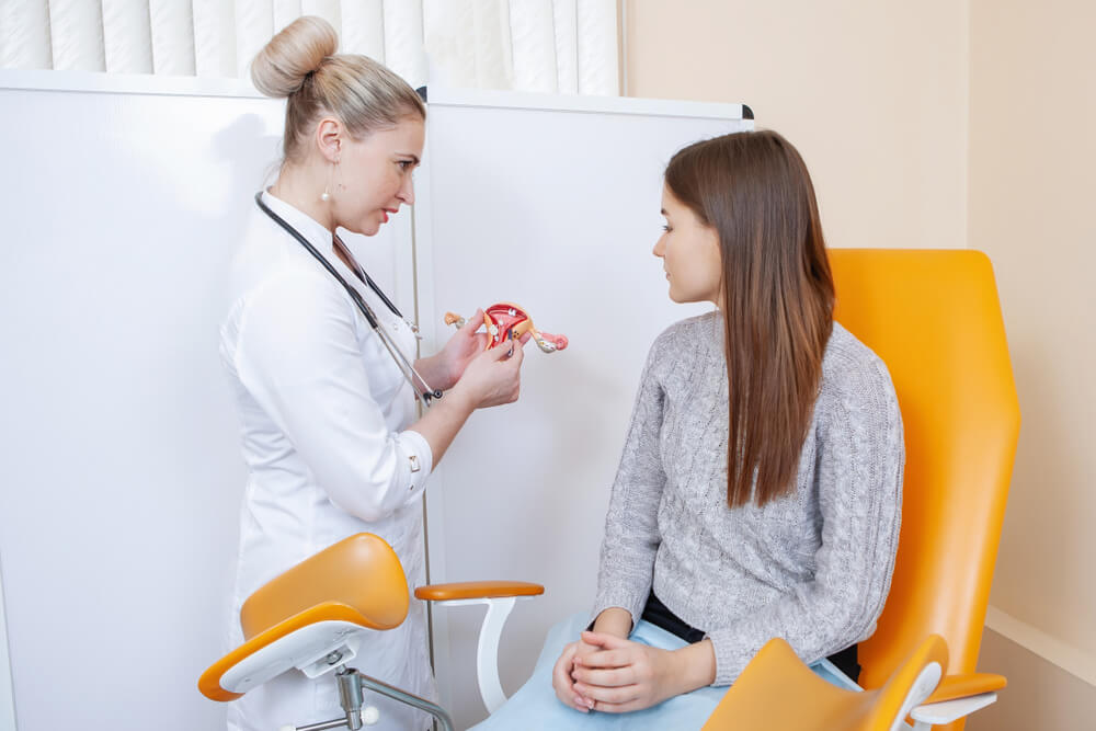 Doctor Gynecologist Talking to a Female Patient in an Orange Chair in a Medical Office.