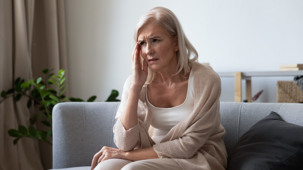 Unhappy Mature Woman Touching Head, Feeling Strong Headache, Sitting on Couch at Home Alone