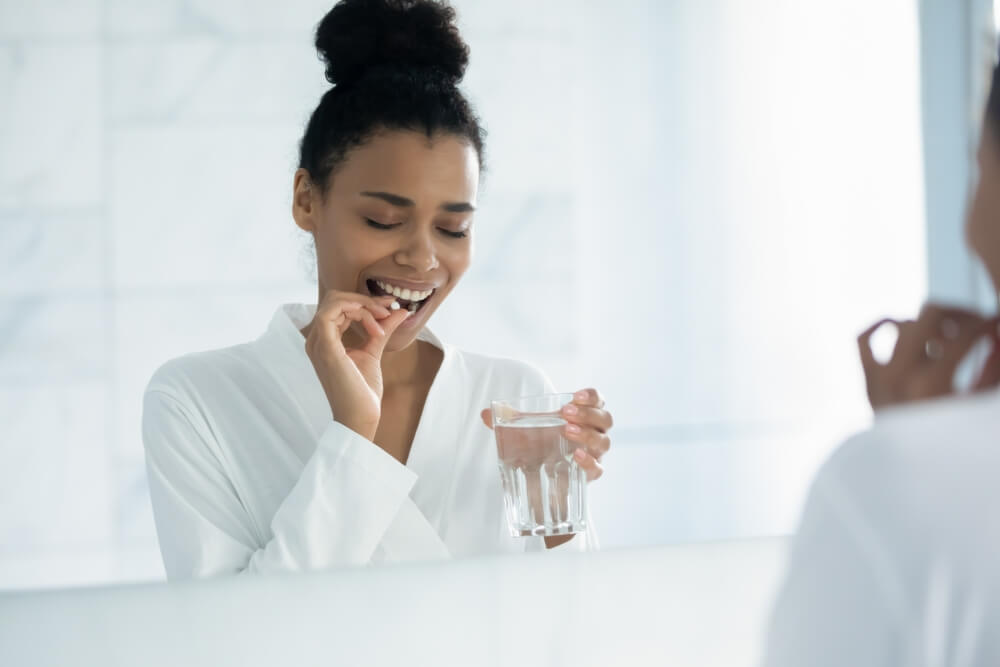 Happy Young Woman Taking Pill