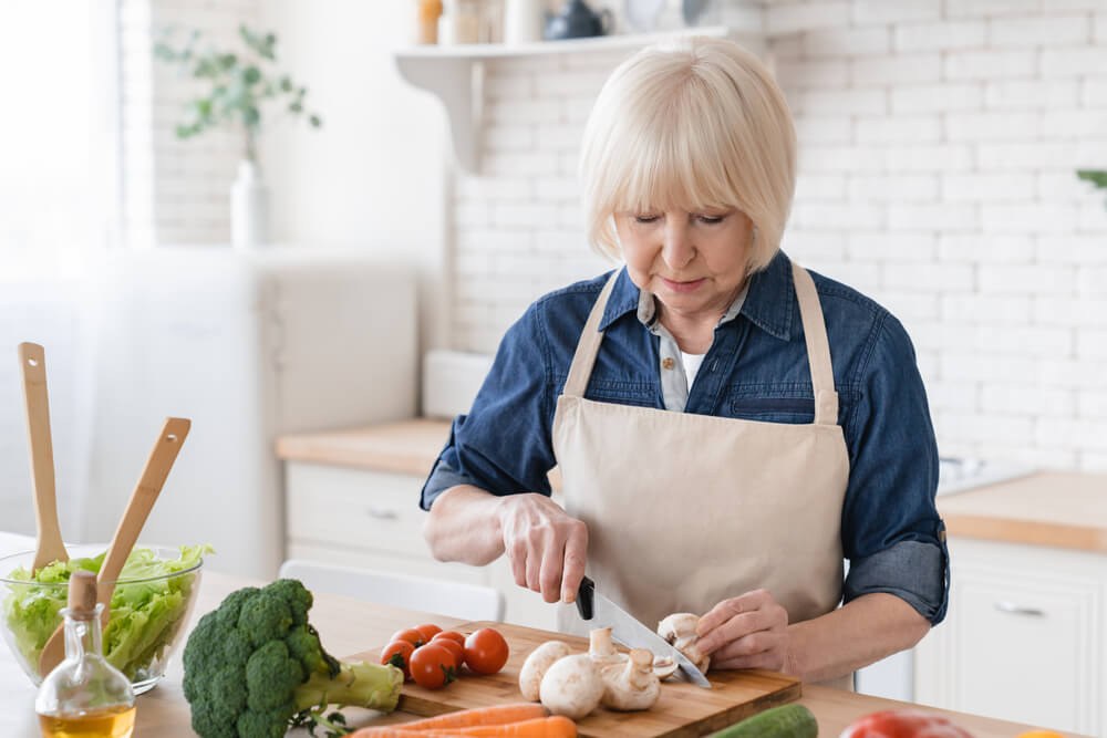 Senior Old Eldery Aged Woman Grandmother Cooking Salad in Kitchen at Home.