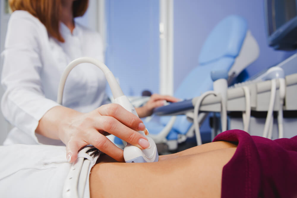 Female Doctor Operating Ultrasound Scanner Examining Belly of Her Female Patient