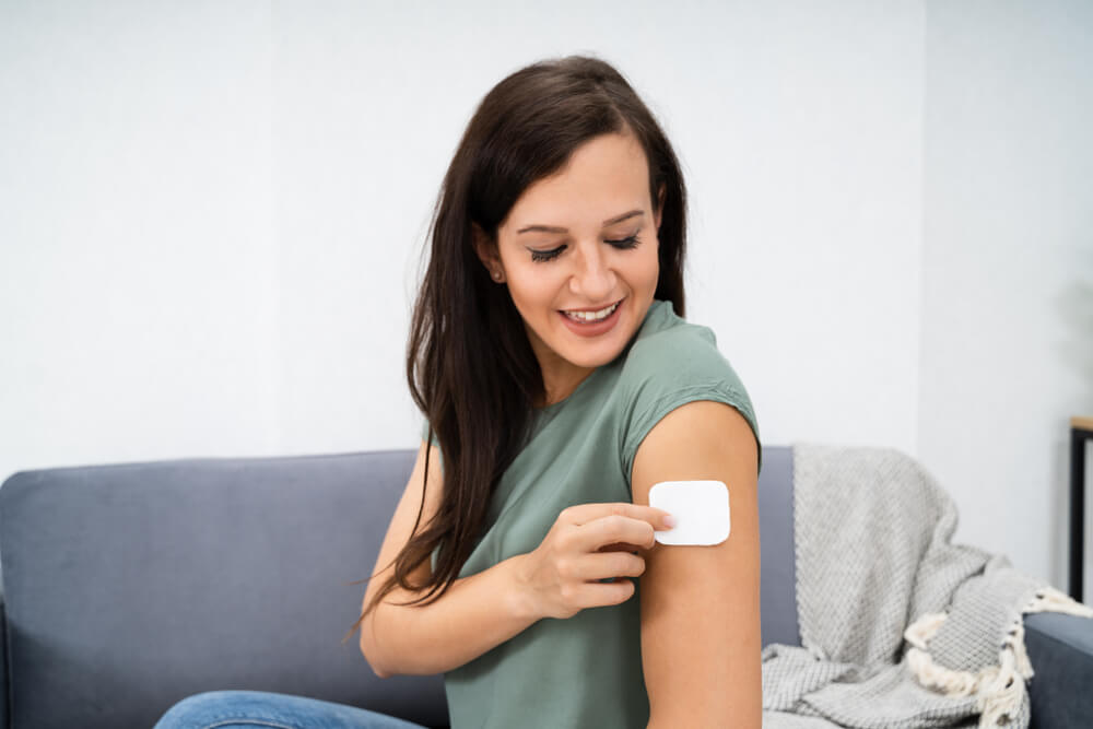 Woman Applying Patch On Her Arm At Home