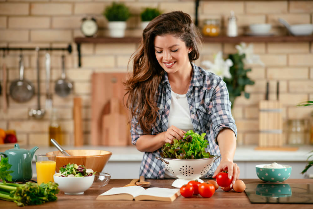 Beautiful Young Woman Is Preparing Vegetable Salad in the Kitchen